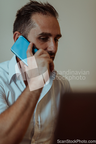 Image of A businessman talking on his smartphone while seated in an office, showcasing his professional demeanor and active communication.