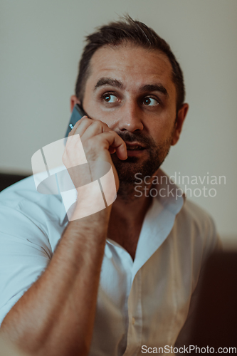 Image of A businessman talking on his smartphone while seated in an office, showcasing his professional demeanor and active communication.