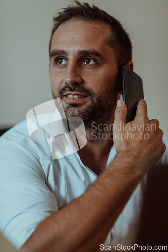 Image of A businessman talking on his smartphone while seated in an office, showcasing his professional demeanor and active communication.