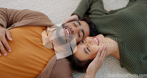 Image of Kiss, love and couple on the floor of their living room to relax with happiness together in their house. Comic, happy and man and woman with smile for affection and funny conversation from above
