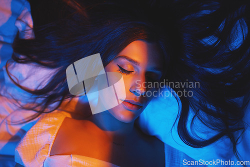 Image of Sleeping, vaporwave lights and woman with eyes closed in bedroom with creative disco lighting. Makeup, beauty and model resting and feeling relax and calm on a bed pillow with cyberpunk aesthetic