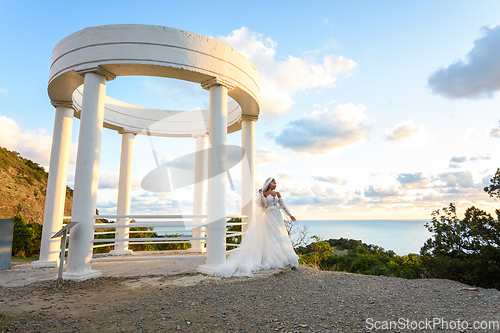 Image of Portrait of a bride in a wedding dress in a beautiful gazebo with columns on the seashore