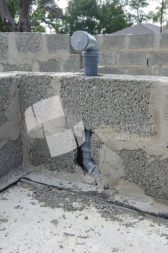 Image of Wall-mounted sewer pipe for a washbasin in a bathroom during the construction of walls from expanded clay concrete blocks