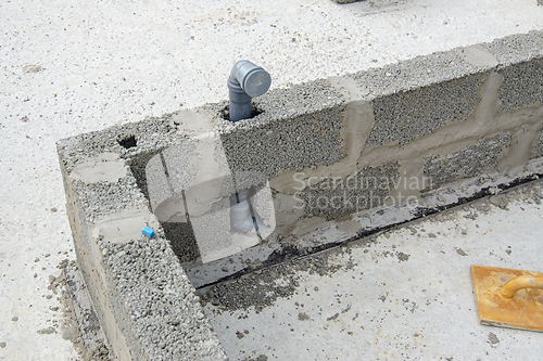Image of The sewer pipe is immured into the wall during the construction of walls from expanded clay concrete blocks
