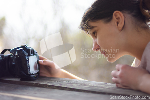 Image of A girl looks at the screen of a SLR camera