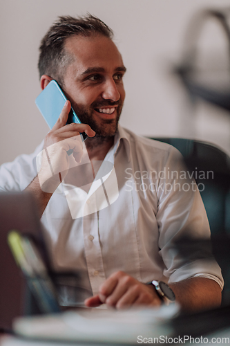 Image of A businessman talking on his smartphone while seated in an office, showcasing his professional demeanor and active communication.