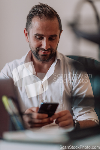 Image of A businessman using on his smartphone while seated in an office, showcasing his professional demeanor and active communication.