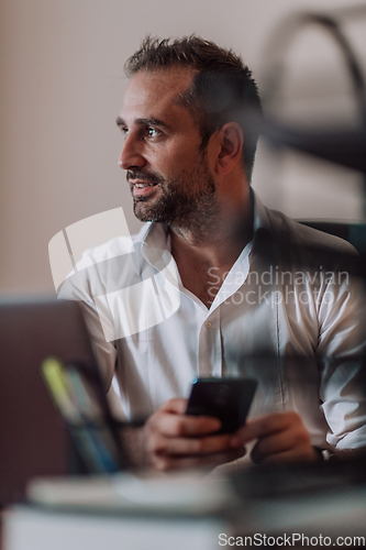 Image of A businessman using on his smartphone while seated in an office, showcasing his professional demeanor and active communication.