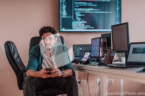 Image of A programmer diligently testing smartphone applications while sitting in their office.