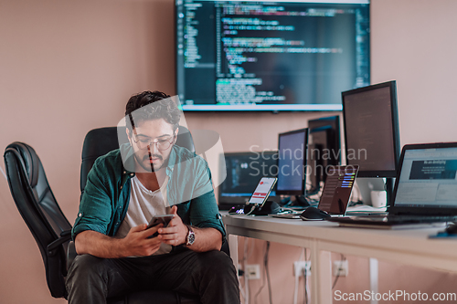 Image of A programmer diligently testing smartphone applications while sitting in their office.
