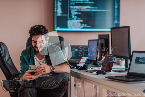 Image of A programmer diligently testing smartphone applications while sitting in their office.