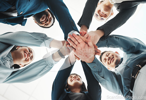 Image of Business people, hands together and unity below for agreement, teamwork or collaboration at office. Low angle of group piling hand in team meeting, partnership or support and motivation at workplace