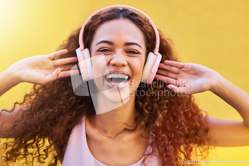 Image of Music, portrait and freedom with a black woman listening to the radio outdoor on a yellow wall background. Headphones, energy and face with an attractive young female streaming audio sound for fun