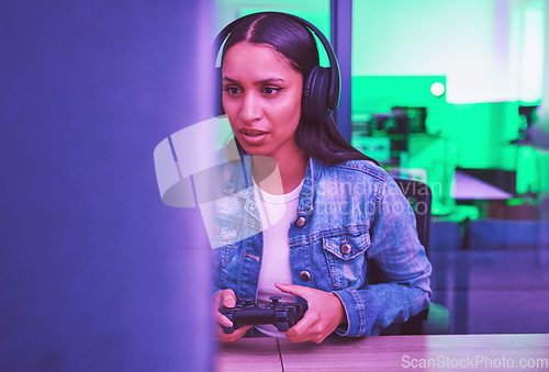 Image of Gamer, headphones and woman on computer in home at night in green neon light for web esports. Gaming, technology and female with controller playing online games, multiplayer or video game in house.