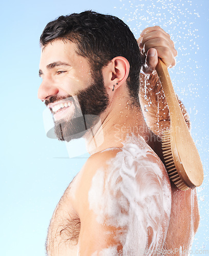 Image of Shower, cleaning and man with brush, water splash and soap in studio for wellness, hygiene and grooming. Skincare, self care and male with foam, bath cosmetics and washing body on blue background