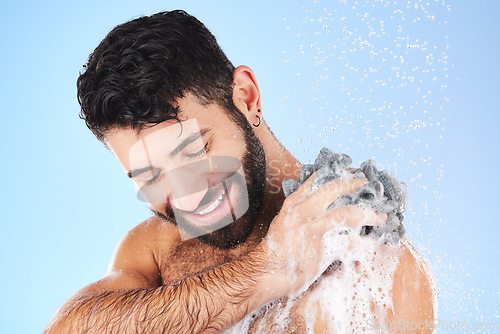 Image of Shower, loofah and man in studio for grooming, hygiene and wellness with soap against blue background. Body care, skincare and male model relax with luxury, foam and product, exfoliation and cleaning
