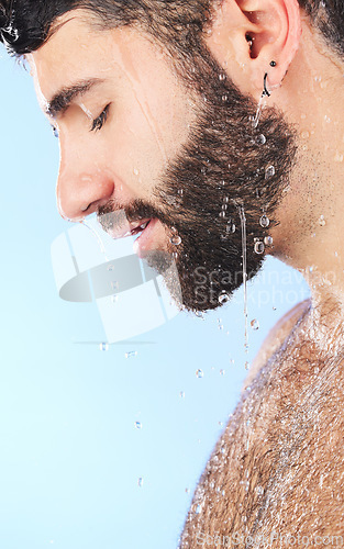 Image of Water, shower and profile of a man in bathroom for cleaning, skincare and hygiene wellness. Isolated, blue background and studio with a male model with dermatology facial and self care routine