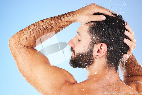 Image of Man, shower and hair wash of a model in water for cleaning, skincare and hygiene wellness. Isolated, blue background and studio with a young person in bathroom for dermatology and self care routine