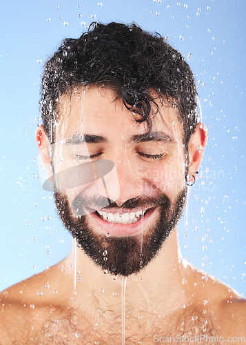 Image of Man, shower water and smile of a model for beauty cleaning, skincare and hygiene wellness. Isolated, blue background and studio with a young person in bathroom for dermatology and self care routine