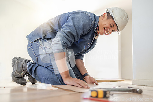 Image of Handyman, wood flooring installation and happy at workplace, industry and home development vision. Black man, construction worker and floor with smile, helmet and tools for diy, interior and design