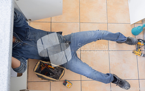 Image of Top, plumber and man on floor of maintenance service, engineering or renovation in house. Above of handyman, plumbing and contractor working with mechanic tools for home pipe, upgrade or installation