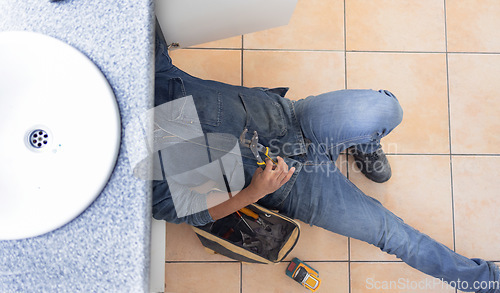 Image of Top view, plumbing and man on floor of maintenance service, engineering or renovation in house. Above of handyman, plumber and contractor with mechanic tools of home upgrade, builder project or pipes