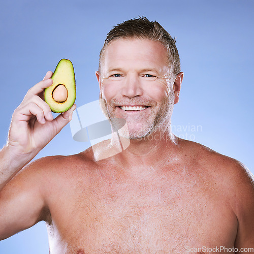 Image of Beauty, portrait with man and avocado for skincare, eco friendly and vegan cosmetics on blue background. Hygiene, organic product and mature male with smile, detox facial and fruit with face care