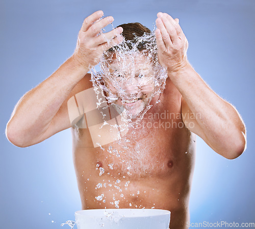 Image of Man, water splash and face wash by basin for hygiene or natural sustainability against a blue studio background. Male washing by sink for clean wellness, skincare or self care for facial treatment