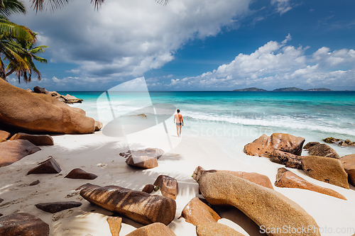 Image of Man enjoying Anse Patates picture perfect beach on La Digue Island, Seychelles.