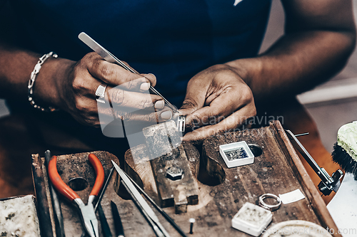 Image of Jeweler making handmade jewelry on vintage workbench.