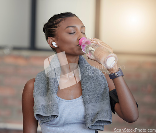 Image of Woman, fitness and drinking water for hydration, workout break or thirsty from intense training at gym. Tired female with bottle or refreshment for thirst, recovery and sweat towel in cardio exercise