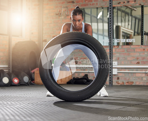 Image of Fitness, exercise and portrait of woman with tire at gym for health and wellness with training workout. Indian athlete person focus on hard work and commitment to train for strong body goals or power