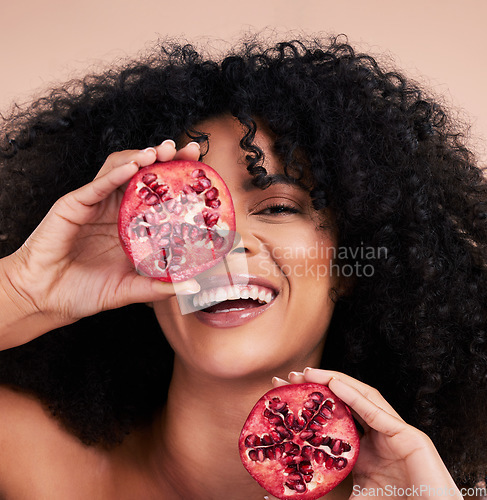 Image of Black woman, studio portrait and pomegranate with smile, beauty and skincare for health, wellness and diet. Happy gen z model, african and fruit for aesthetic, healthy nutrition or glow by background