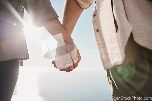 Image of Love, unity and couple holding hands on the beach while on a date for romance or their anniversary. Trust, support and closeup of man and woman with hand intimacy and affection while on outdoor walk.