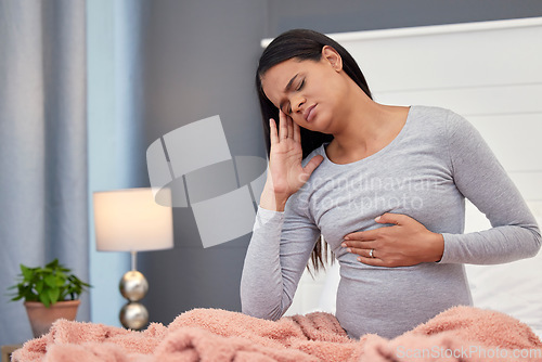 Image of Pregnancy, headache and woman in bed, pain and stress with maternity issues, anxiety and touching stomach. Pregnant, female and lady with ache, migraine and contractions in bedroom and frustrated
