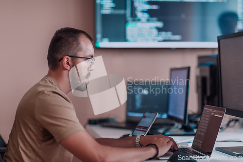 Image of A programmer diligently testing smartphone applications while sitting in their office.