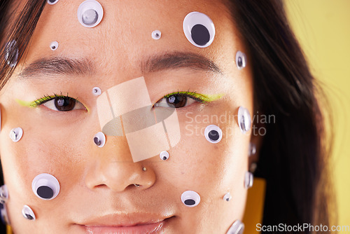 Image of Gen z, eyes sticker art and portrait of an Asian woman with makeup and colorful cosmetics. Creative googly eye application, style influencer and cosmetic creativity of a model with studio background