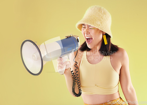 Image of Asian, girl and studio with megaphone for protest, shout and speech for human rights by background. Young gen z model, loudspeaker voice and yellow 90s aesthetic for change, justice or opinion