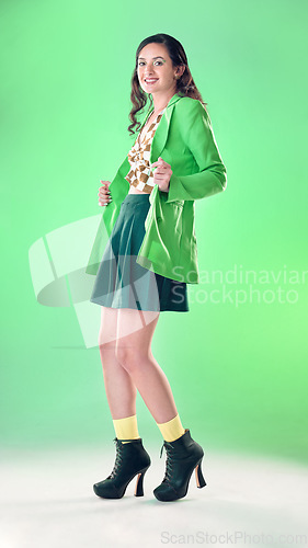 Image of Fashion, beauty and portrait of a woman in a studio with a trendy, stylish and edgy outfit. Happy, smile and young female model with style and cool clothes posing while isolated by a green background