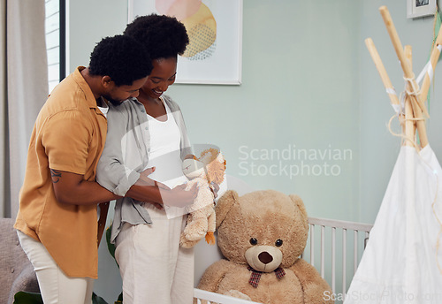 Image of Love, teddy bear and pregnant couple in the nursery with excitement while preparing for their baby. Happy, pregnancy and young African man with his maternal wife looking at toy together in bedroom.