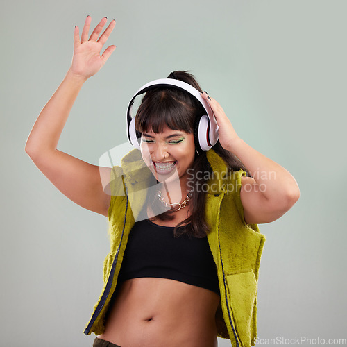 Image of Punk, dance and woman with headphones, celebration and music streaming against grey studio background. Hipster, female and happy lady with headset, smile or sounds with trendy, stylish or edgy outfit