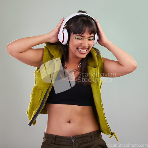 Image of Music, dance and woman with headphones in studio, happy and excited isolated on grey background. Streaming service, song and gen z fashion, girl dancing with hands up and smile to online radio dj.