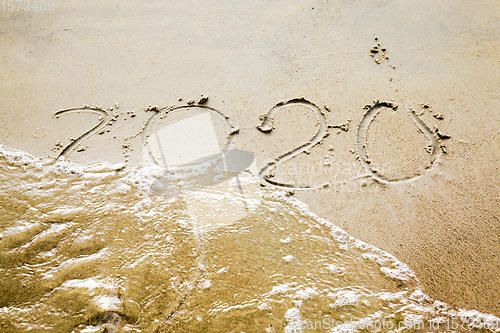 Image of sea waves erasing the inscription of 2020