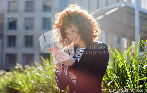 Image of Business woman, phone and smile for communication, social media or texting and chatting in city. Happy female ginger typing and smiling on smartphone for 5G connection, mobile app or networking