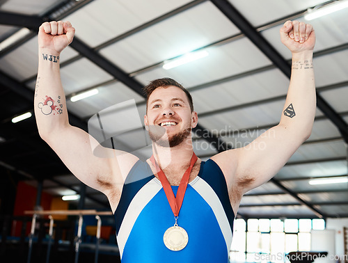 Image of Man, medal celebration and winner with smile, indoor sports or hands in air at competition with pride. Champion athlete, happy and winning with gold, celebrate or success in global gymnastics contest