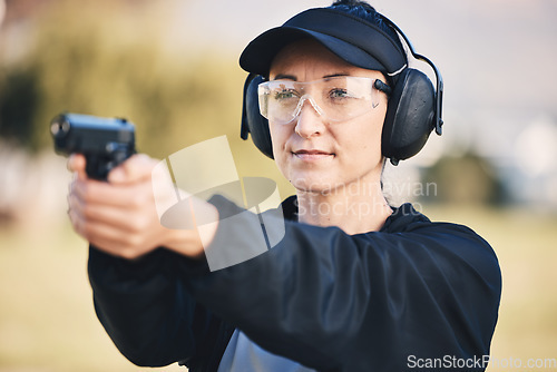 Image of Woman, gun and learning to shoot weapon at shooting range outdoor for security, training and target. Person with safety headphones and glasses for sport, competition or safety with gear in hands