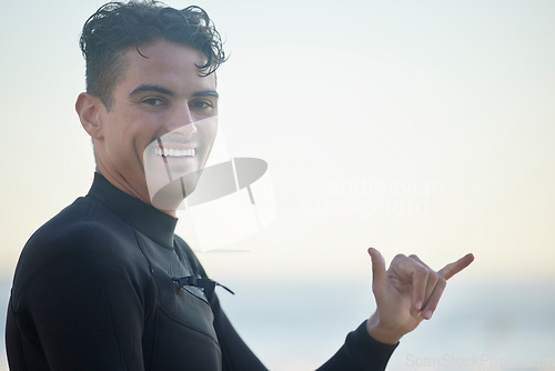 Image of Shaka, portrait and man surfer at the beach for water sports training or exercise while on vacation. Happy, smile and male athlete with a hang loose hand sign ready for a surfing workout in Australia