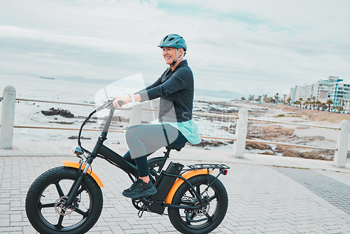 Image of Fitness, senior woman and bicycle on promenade, exercise and training for wellness, beach and break. Mature female, elderly lady and biker commute, travel and workout outdoor, seaside and motorcycle