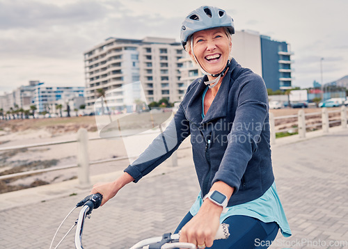 Image of Fitness, promenade and woman riding a bicycle for exercise, health and wellness by the beach. Sports, smile and portrait of happy senior female cyclist cycling for outdoor cardio workout or training.