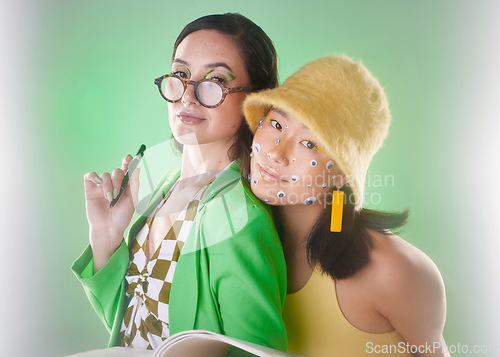 Image of Portrait, gen z and and books with woman friends in studio on a green background for fashion or education. Beauty, cosmetics and friendship with people posing for modern or contemporary neon style